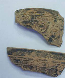 أدوات فخار ملونه بالأسود إلى جانب مسكه لقارورة عليها ختم باللغة اليونانية