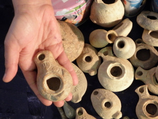 A rare Roman lamp bearing an incised decoration of a seven-branched menorah. In the background – other clay lamps that were seized from the suspect